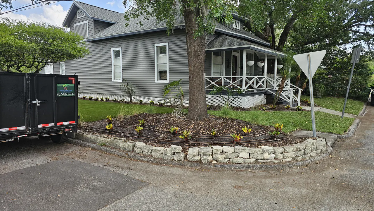A Woods company trailer beside a new stone-edged corner planting bed with crotons