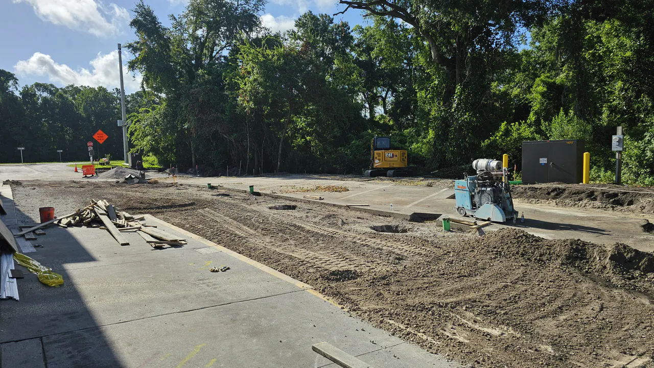 A commercial lot excavated and graded with a mini excavator and a concrete saw on site